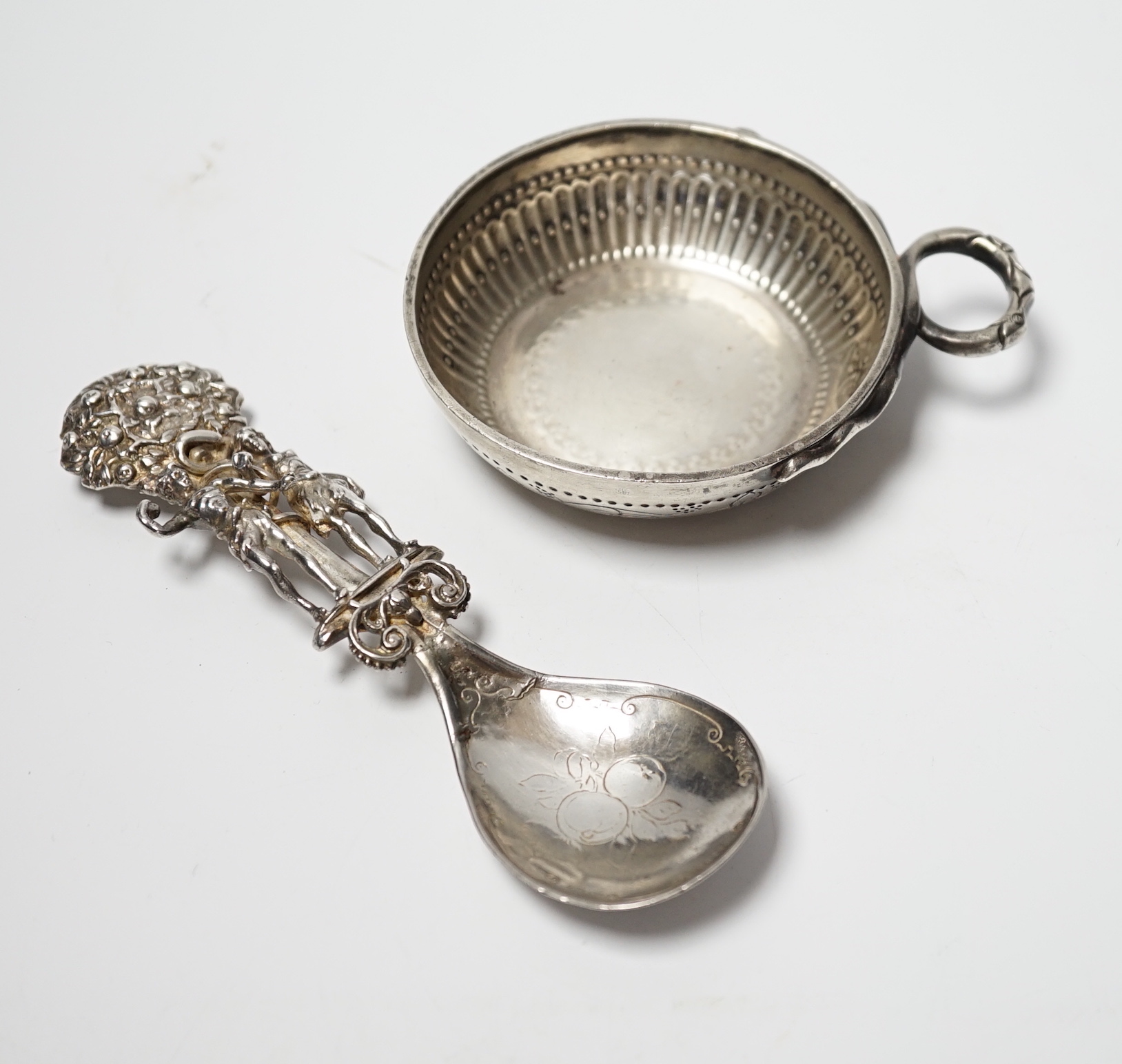 A George V silver taste vin, C.J. Vander Ltd, London, 1932, diameter 81mm, together with a Hanau ornate silver spoon, depicting Adam and Eve with the serpent, import marks for Berthold Muller, London, 1903, 14cm.